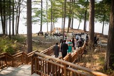 a group of people standing on top of a wooden bridge in the woods next to trees