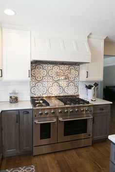 a stove top oven sitting inside of a kitchen next to white cabinets and counter tops