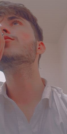 a man in white shirt holding a cell phone to his ear