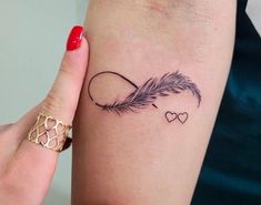 a woman's arm with a feather and heart tattoo on the left side of her arm