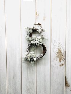 a wreath hanging on the side of a white wooden wall with snowflakes and berries