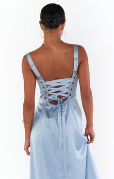 the back of a woman wearing a light blue dress with cut outs and straps on it