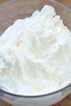 a glass bowl filled with whipped cream on top of a wooden table