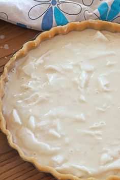 an uncooked pie crust sitting on top of a wooden table next to a blue and white towel