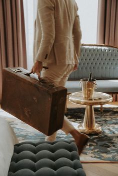 a man carrying a suit case across a living room with a coffee table and couch