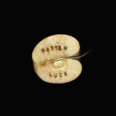 an apple sliced in half with the words rotten lucky written on it