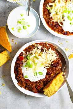 two bowls of chili with cornbreads and sour cream