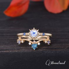 two rings with blue and white stones are on top of a wooden table next to flowers