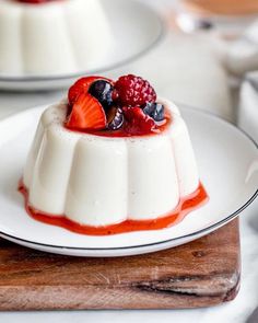 a dessert with fruit on top is sitting on a white plate next to another dish