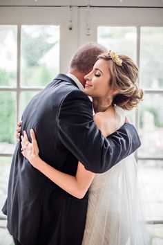 a bride and groom embracing each other in front of large windows