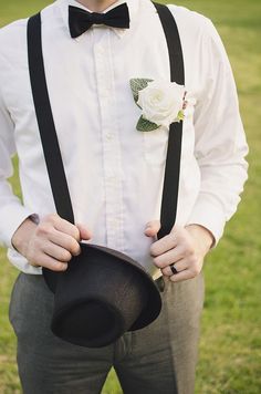 a man in a white shirt and black bow tie with a hat on his shoulder