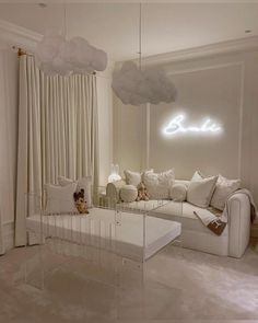 a living room filled with white furniture and clouds hanging from the ceiling over it's windows