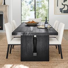 a dining room table with white chairs and a bowl of food on top of it