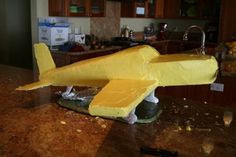 a yellow model airplane sitting on top of a counter in a kitchen next to a sink