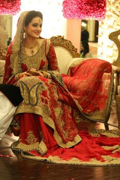 a man kneeling down next to a woman in a red and gold wedding dress