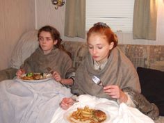 two women sitting on a couch eating food