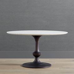 a white table sitting on top of a hard wood floor next to a gray wall