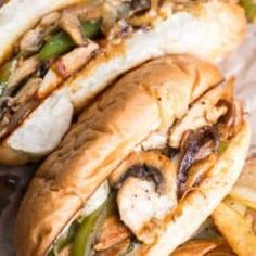 two sandwiches with mushrooms, peppers and french fries