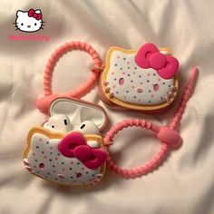 two hello kitty cell phones are laying on a white sheet and one has a pink hair band