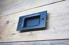 a black square light switch mounted on a wooden wall next to a wood plank floor