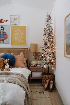 a bedroom with a christmas tree in the corner and pictures on the wall above it