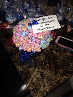 a bowl filled with lots of candy sitting on top of a table next to a cell phone