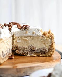 a piece of cheesecake with pecans and nuts is on a cutting board next to the rest of the pie