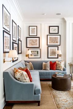 a living room filled with lots of furniture and framed pictures on the wall above it