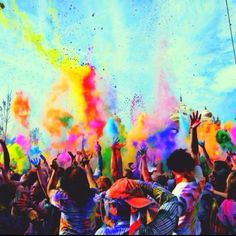 people are throwing colored powder in the air at a festival with their hands up to the sky