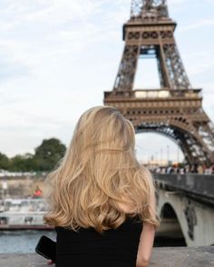 a woman sitting in front of the eiffel tower with her back to the camera