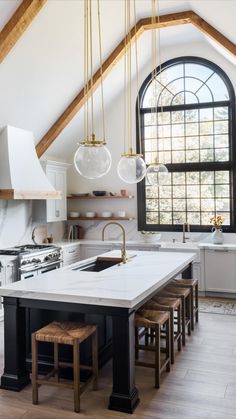 a large kitchen with an island and two stools in front of the counter top