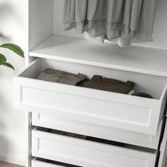 a white cabinet with shoes and towels in it