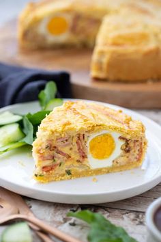 an egg pie on a white plate with cucumbers and sauce in the background