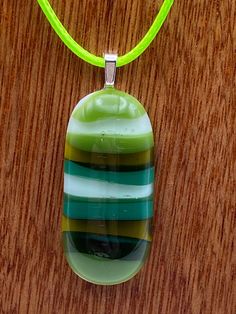 DragonFusedGlass are proud to sell this green stripes design fused glass necklace and matching earring set. We have used shades of green glass and fused them on to a clear glass background to create this hand crafted this absolutely beautiful tactile pendant This utterly unique pendant is supplied on a 45cm green coloured cord and comes in its own presentation box. Due to the kiln firing process, every creation is unique and therefore no two items created will ever be totally the same.  The photographs displayed here are of the actual finished product for sale, so that what you see is the unique item you will own.  Thank you for viewing and please do look at our other creations in our Etsy Shop: https://dragonfusedglass.etsy.com Handmade Modern Green Jewelry, Green Handmade Modern Jewelry, Modern Handmade Green Jewelry, Modern Green Handmade Jewelry, Green Glass Jewelry Gift, Green Glass Jewelry As Gift, Green Glass Jewelry As A Gift, Adjustable Green Recycled Glass Necklace, Green Glass Pendant Jewelry