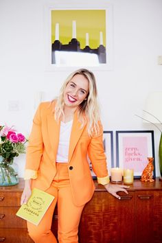 a woman in an orange suit is posing for the camera