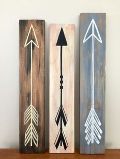 three wooden signs with arrows painted on them sitting on a shelf next to each other