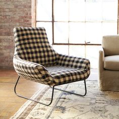 a chair sitting on top of a wooden floor next to a couch in front of a window