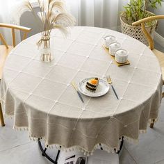 a table with a cake on it and two chairs in front of it, next to a potted plant