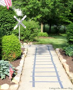 a walkway in the middle of a park with flags on it and trees around it