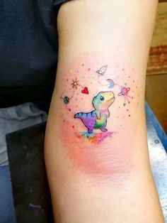 a small tattoo on the arm of a woman's left arm, with an image of a dinosaur and stars