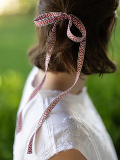 a woman wearing a white shirt and red ribbon around her neck is standing in the grass