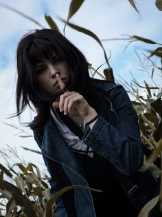 a woman standing in the middle of a corn field holding her finger to her lips