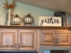 a kitchen with wooden cabinets and a sign that says gather on the top above it