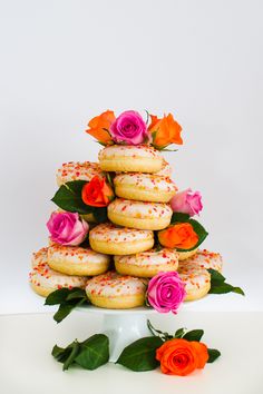 a white cake stand topped with donuts covered in frosting and sprinkles