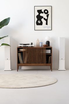 a living room with white walls and an area rug that has a wooden cabinet on it