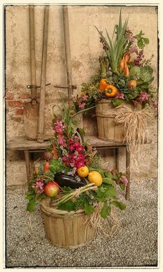 two baskets filled with fruits and vegetables sitting on top of a wooden bench next to a wall