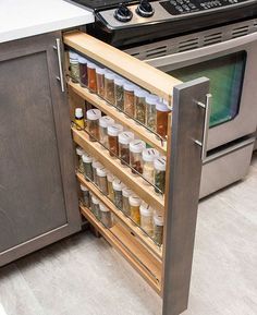 an open cabinet in the middle of a kitchen with spices and condiments on it