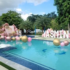 an outdoor pool decorated with pink and gold balloons