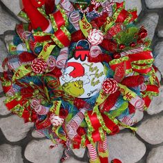 a christmas wreath with candy canes and santa's helper on it sitting on some rocks