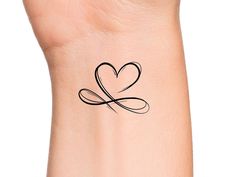 a small heart tattoo on the wrist with an arrow in the shape of a heart